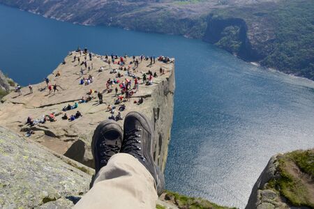 View over the world famous Preikestolen - or pulpit rock - over the Lysefjord, Norway, with hiking boots in the foregroundの写真素材