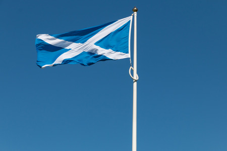 Traditional Scottish flag in front of a clear blue sky, flapping in the wind of the Highlands shortly before the referendum on Independenceの写真素材