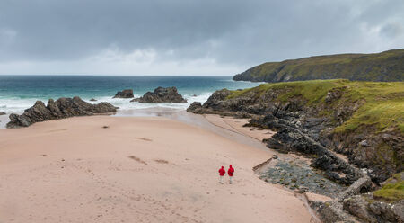 Rocks at famous Sango Beach bay near Durness, northern Scotland, with tourists walking along the beachの写真素材