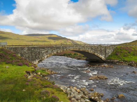 Old stone bridge in Scotland leading over a brook in the Highlandsの写真素材