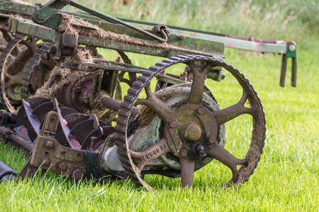 Closeup shot of an old rusty golf course mower on a green meadow
