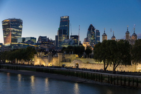 View along the walls of the Tower of London with the modern city skyline in the background at nightのeditorial素材