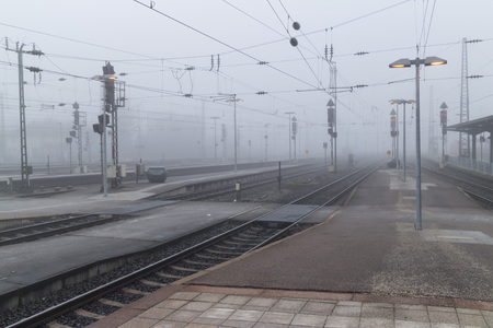 Railroad tracks leading into thick mysterious fog on a cold and wet winter day