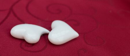 Two porcelain hearts on an ornamented red tablecloth as the festive coffee table  decoration in a restaurantの写真素材