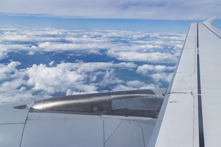 Aerial view of a cloudscape with an airplane turbine and wing in the foreground