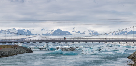 Bridge over world famous Jokulsarlon glacier lagoon in southern Iceland with icebergs swimming in the waterの写真素材