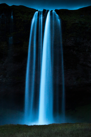 Night shot of world famous Seljalandsfoss, a majestic waterfall in southern Iceland, coming down over a cliff, fed by a glacierの写真素材