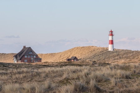Small white lighthouse on a hill with beach grass on Sylt island, Germanyの写真素材