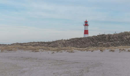 Small white lighthouse on a hill with beach grass on Sylt island, Germanyの写真素材