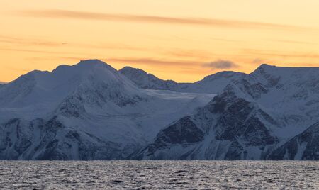 Epic Norwegian fjord and barren, snow covered mountains during sunset, far above the polar circle near Skjervoyの写真素材
