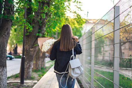 Girl with a bouquet of camomiles. Girl with a backpack and a bouquet of flowers.の写真素材