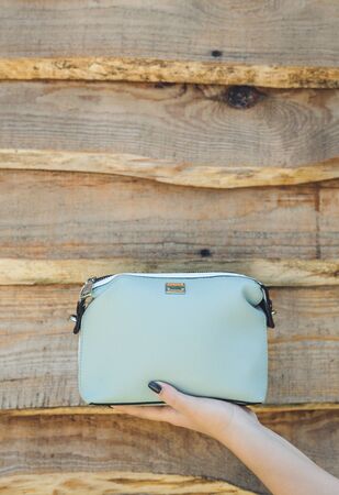 Woman hand holding blue handbag on wooden background.
の写真素材