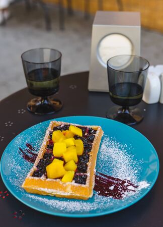 Belgian waffle with mango in blue plate. Belgian waffle and a glass of white wine.
の写真素材