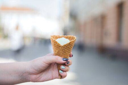 Girl's hand holds vanilla ice cream in waffle cone.
の写真素材
