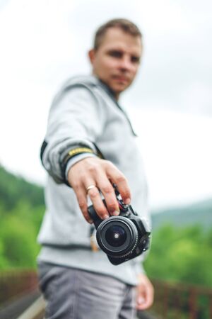 Man photographer holding his camera. Photographer with camera on forest backgroundの写真素材