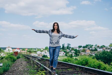 Happy girl at train station in summer sunny day. Brunette girl in jeansの写真素材