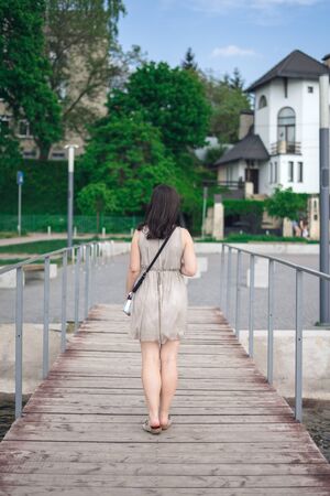 Girl is dressed at the lake. Young woman in gray summer dressの写真素材