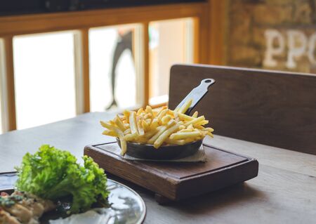 French fries in pan on wooden tableの写真素材