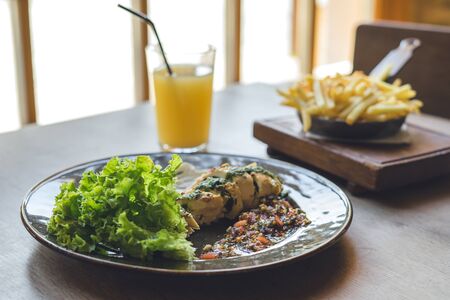 Meat with sauce and salad on wooden table. Glass of fresh juice.