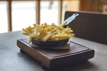 French fries in pan on wooden tableの写真素材