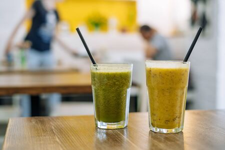 Two glasses of tasty smoothie on wooden table in cafe. Vegetable and fruit smoothiesの写真素材