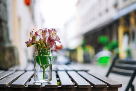 Alstroemeria flowers in vase on wooden table. Pink flowers in glass vase on table in summer cafe. Beautiful flowers in summer dayの写真素材