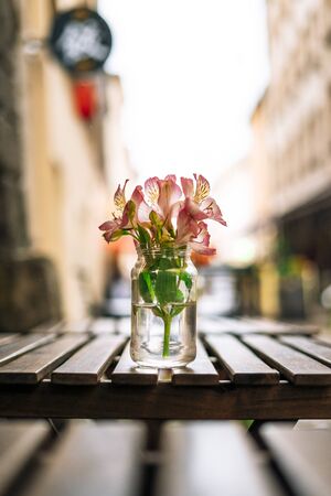 Alstroemeria flowers in vase on wooden table. Pink flowers in glass vase on table in summer cafe. Beautiful flowers in summer dayの写真素材