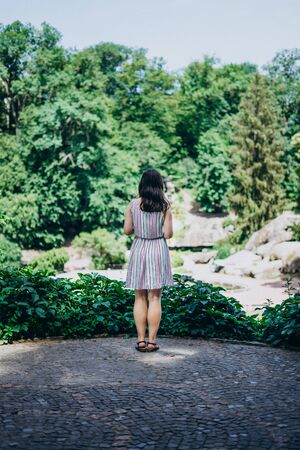 Sofia Park, Ukraine. Young girl in a beautiful summer park. Brunette girl in a colored sundress. Girl tourist on the observation deck in the parkの写真素材