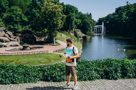 Sofia Park, Ukraine. Handsome man with a beard in a dendrological park. Man with a backpack on the background of the lake with a fountain and a white gazebo.の写真素材