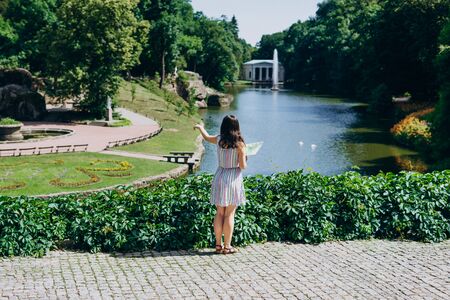 Sofia Park, Ukraine. Young woman with a tourist map walks in a landscaped park. Girl with a tourist map on the background of the lake with a fountain.の写真素材