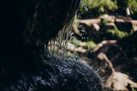 A small natural waterfall. Waterfall in the grotto in the national park. Grotto with water