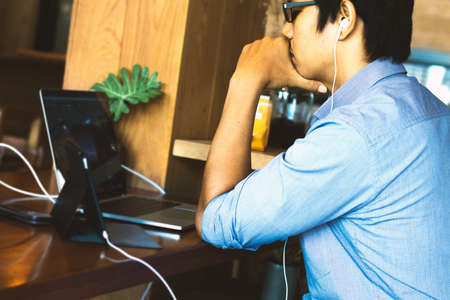 Young man using a laptop and a small torch.の写真素材