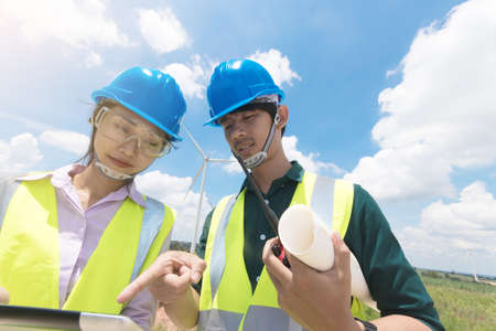 Two male and female engineers are working at the wind turbine.の写真素材