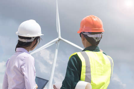Two male and female engineers are working at the wind turbine.の写真素材