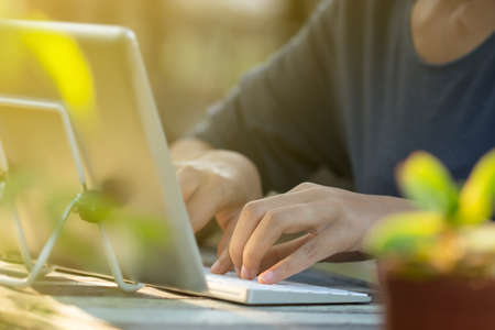 Woman is using a tablet and typing keyboard in the garden.の写真素材
