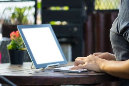 Woman is using a tablet and typing keyboard in the garden.