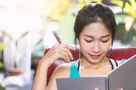 Asian women writing diary in notebook.