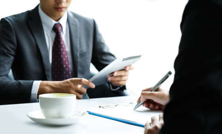 Businessmen and business women are meeting and using a tablet.の写真素材