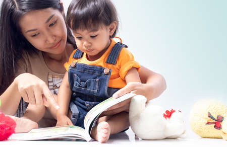 Little girl is playing dolls together with mother.