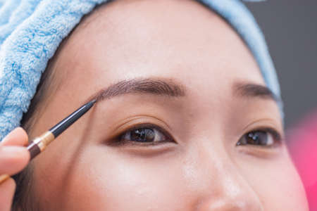 A woman is drawing eyebrows.
