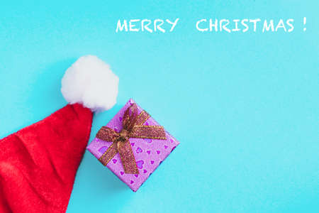 Red Christmas hat and gift box on a blue background.の写真素材