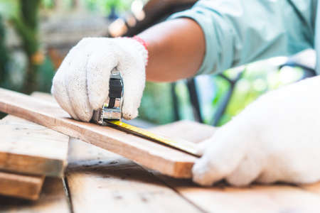 The technician is using a wooden measuring tape for cutting.
