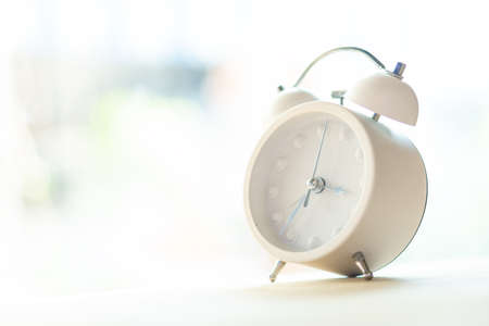 White alarm clock placed on a wooden table and to decorate the houseの写真素材