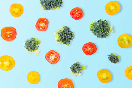 Fresh yellow tomatoes and broccoli blocks on a blue background