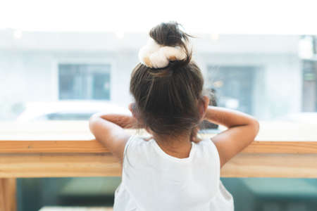 The little girl is sitting alone at the window.の写真素材