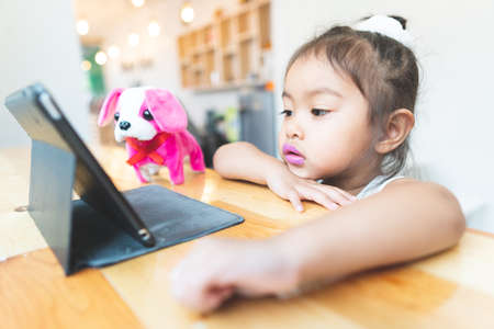 Asian little girl Sitting The tablet is at home.の写真素材