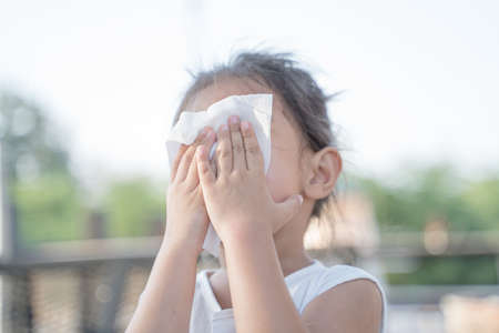 The girl is using a cloth to wipe his nose.の写真素材