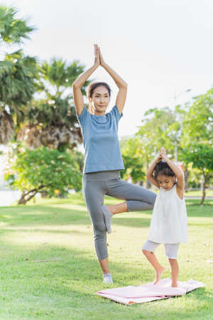 Mother and daughter are doing yoga together in the garden.の写真素材