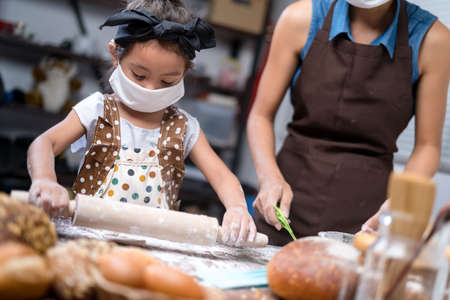 Mother and daughter are baking bread from home.