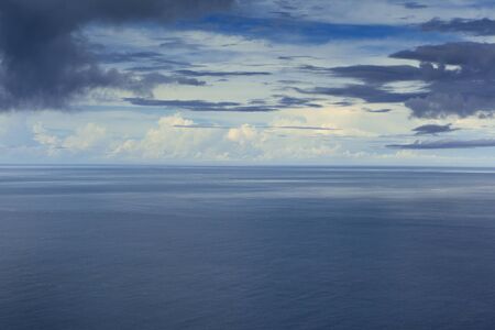 Cloudy blue sky above a blue surface of the sea